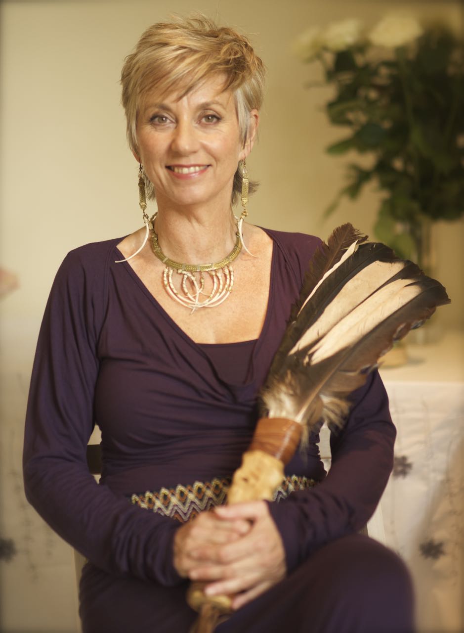 Sue Holmes in purple on her healing journey, holding a condor feather 